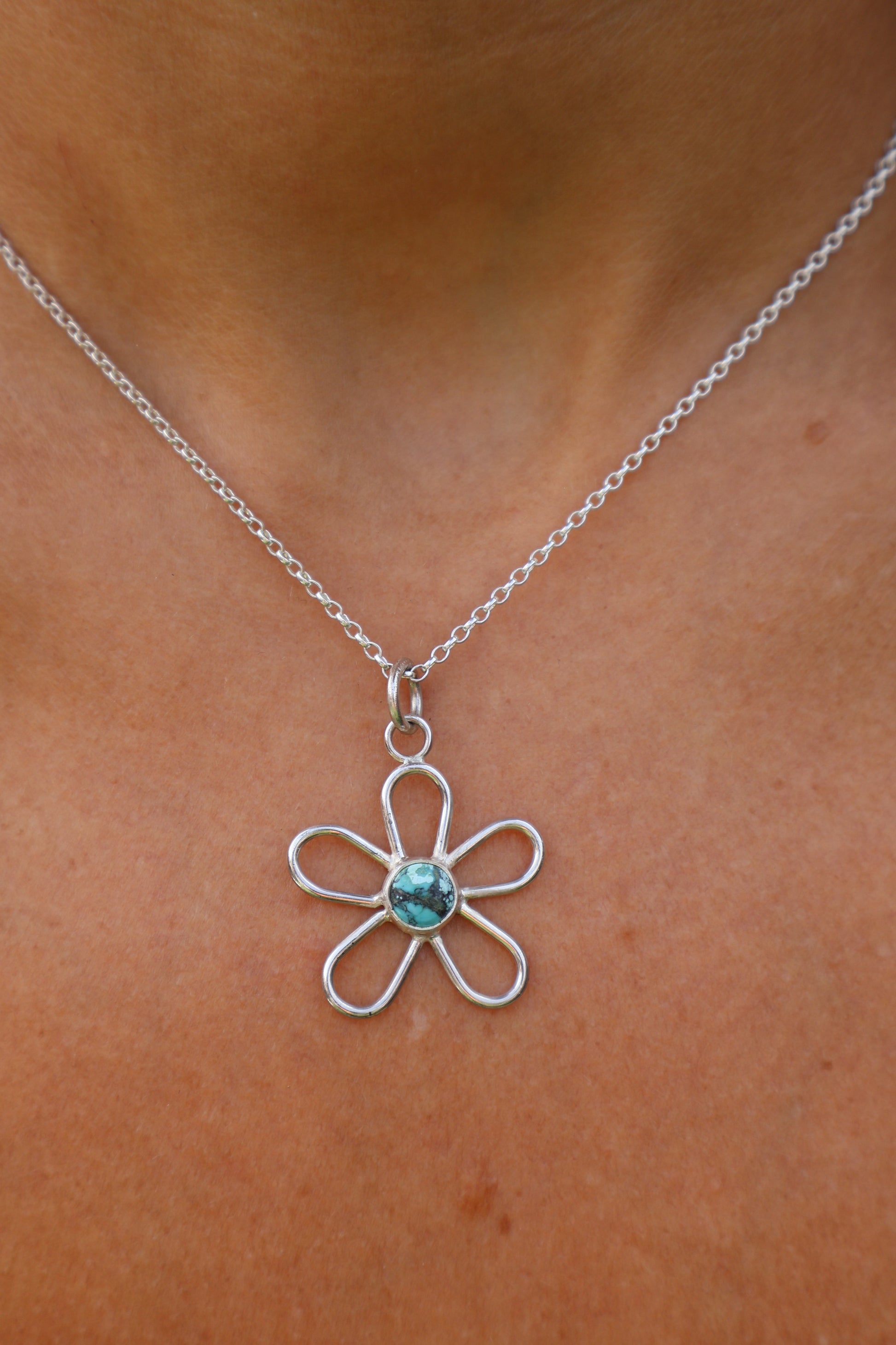 close up of a woman wearing a sterling silver handmade turquoise Tibetan gemstone flower pendant 