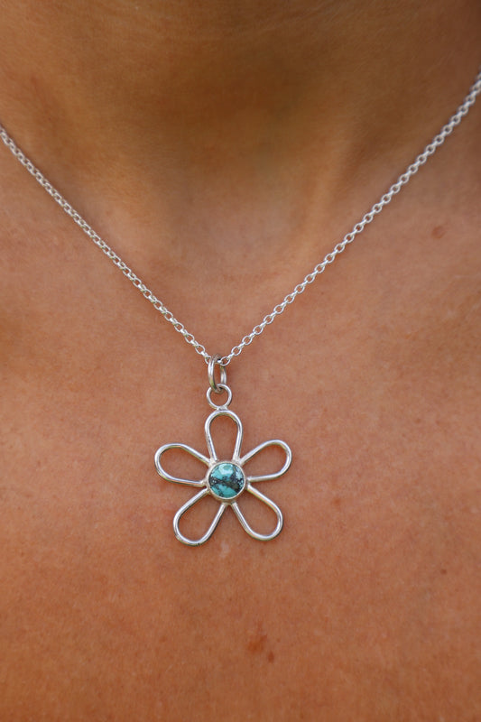 close up of a woman wearing a sterling silver handmade turquoise Tibetan gemstone flower pendant 