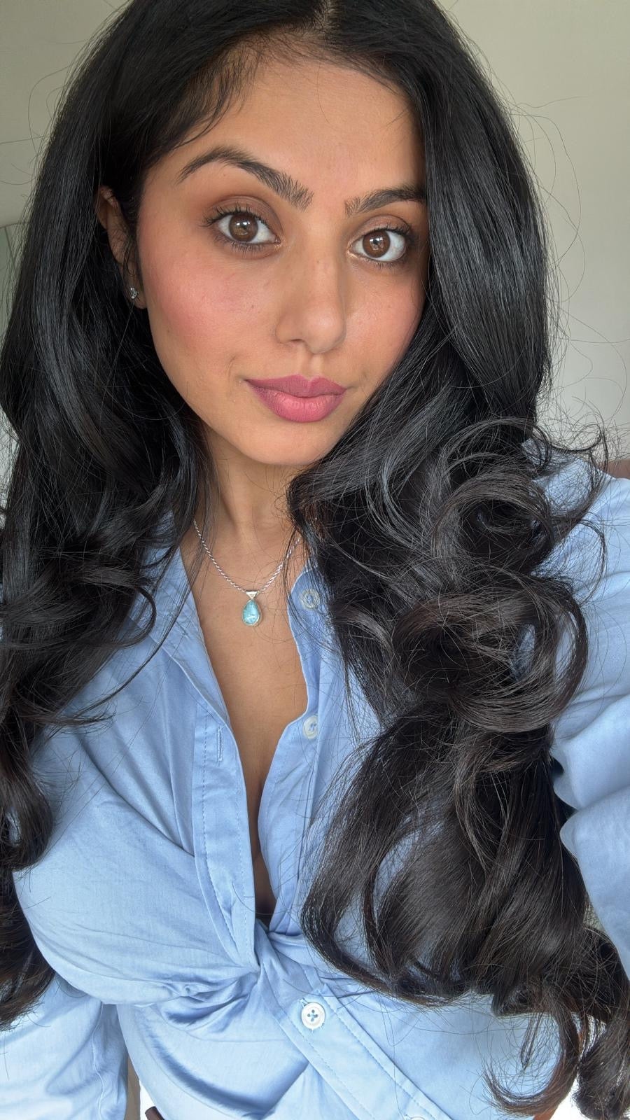 Woman with long, wavy hair wearing a light blue shirt.