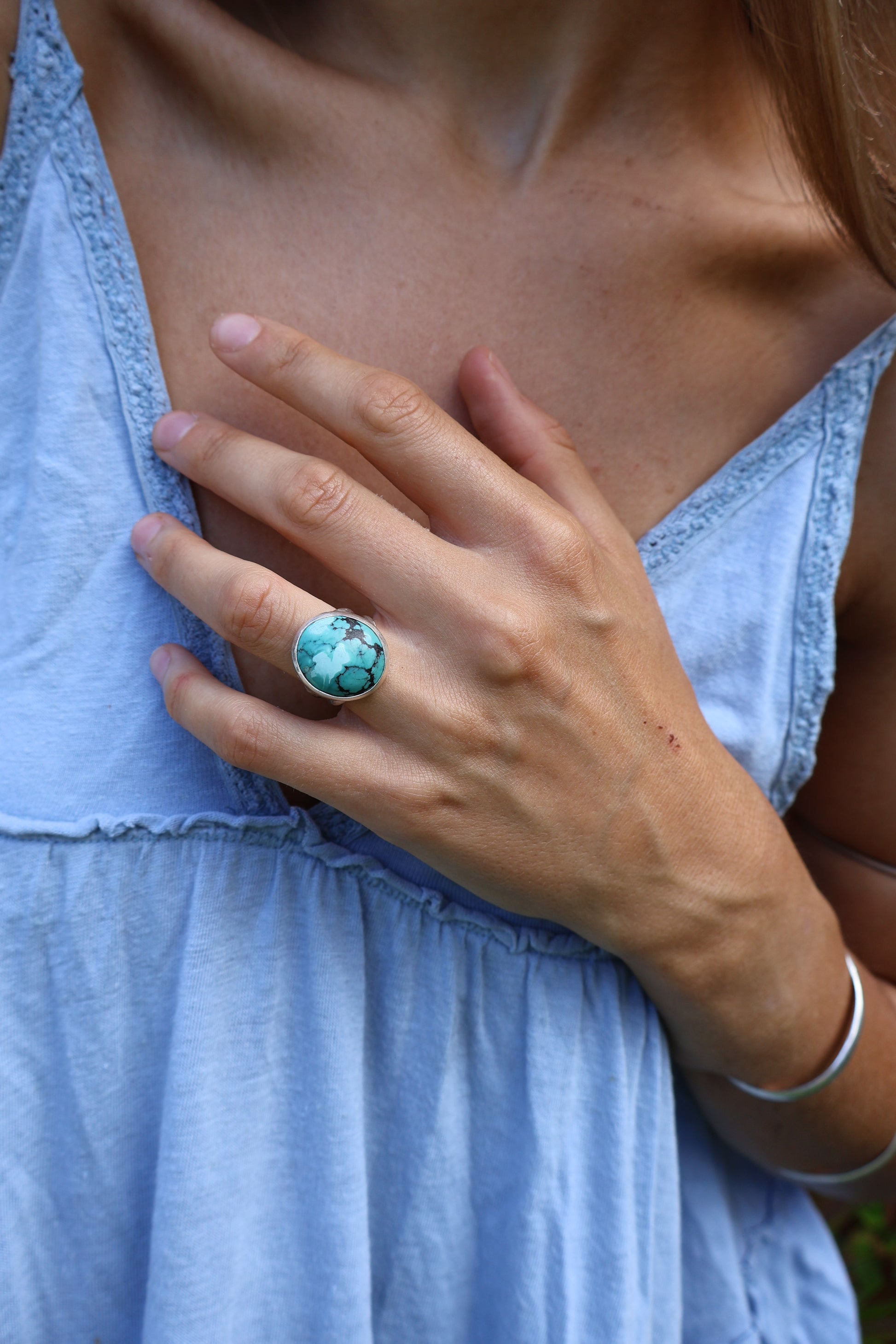 Woman grounding in nature with chunky turquoise statement ring